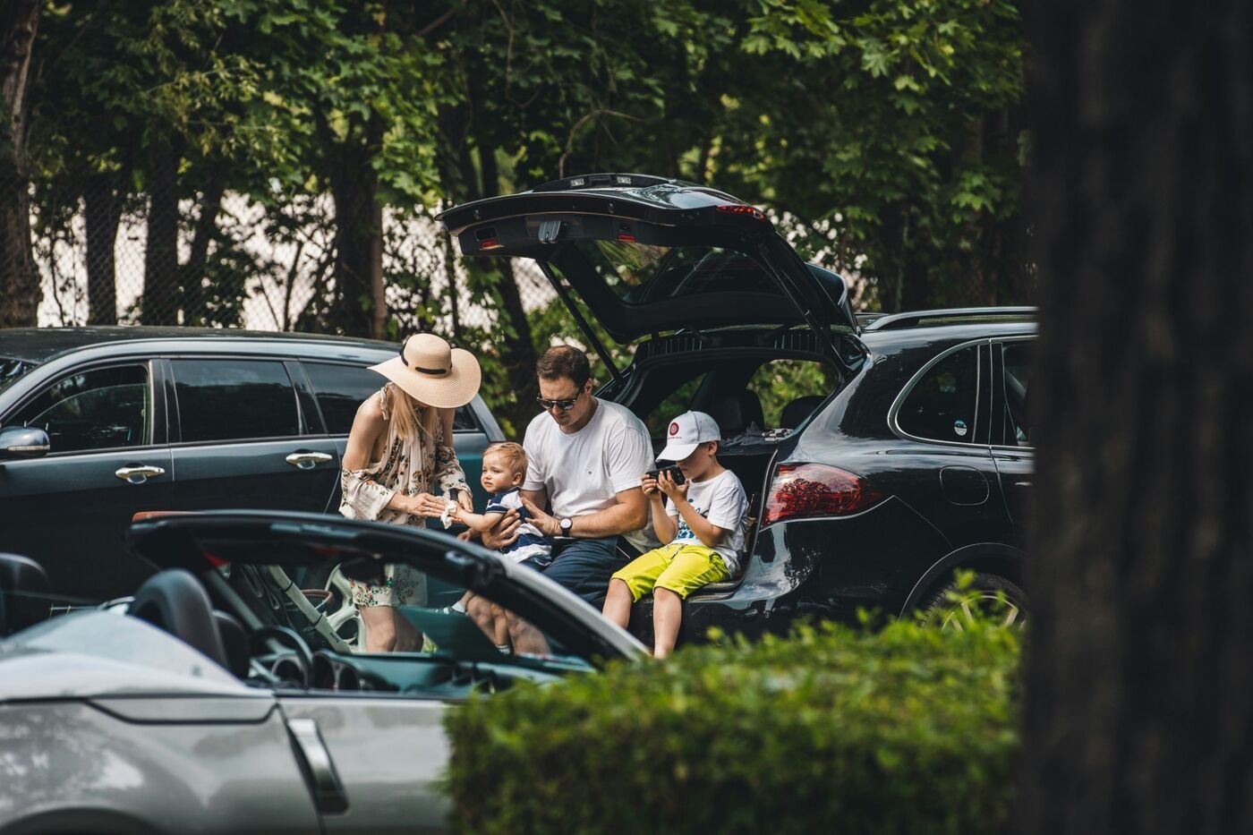 A family sitting at the open boot of their car