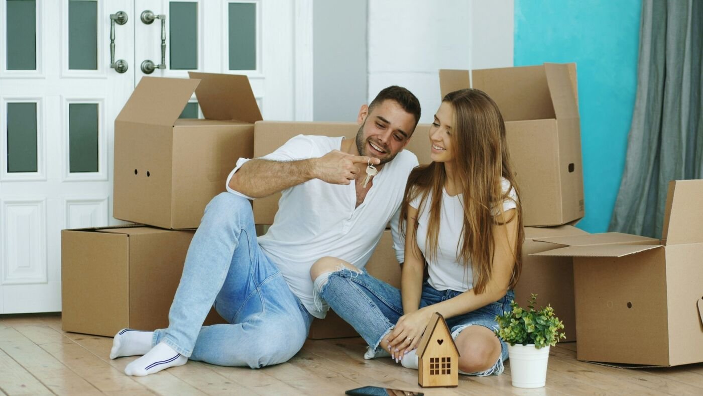 A young couple holding the keys to their first home among moving boxes